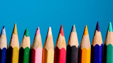 * * Renkli kalemlerin yakın plan çekimleri, canlı mavi bir zemin, yaratıcılık ve sanat malzemeleri sergileniyor.