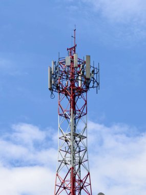 Açık mavi gökyüzüne karşı antenleri olan yüksek bir telekomünikasyon kulesi, teknoloji ve iletişim temaları için ideal..