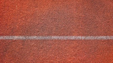 * * Spor ve atletizm temaları için ideal, belirgin beyaz bir çizgi içeren kırmızı koşu pisti yüzeyinin ayrıntılı görünümü