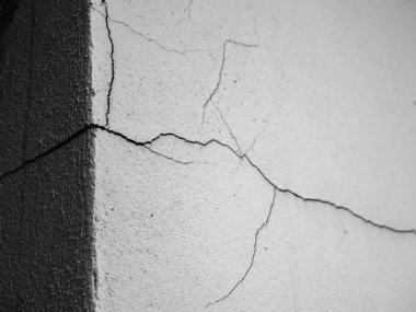 Çatlak bir beton duvarın detaylı siyah beyaz görüntüsü, yapısal hasar ve doku göstergesi..