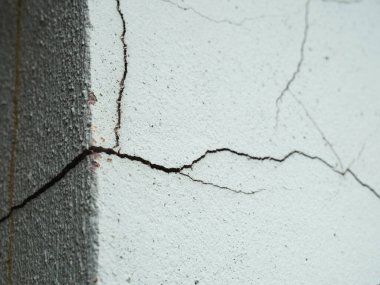 Çatlak bir beton duvarın detaylı görüntüsü, doku ve yapısal kusurları vurguluyor..