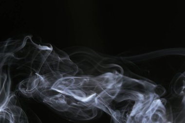 Karanlık bir arkaplanda dönen beyaz dumanın büyüleyici görüntüsü bir gizem ve soyutlama hissi uyandırıyor..