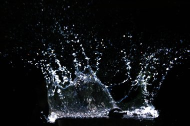 Su damlacıklarının hızlı bir şekilde yakalanması, su sıçratması, hareketlilik ve sıvı dinamikleri karanlık bir zemine karşı..