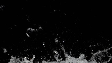 Su damlacıklarının yüksek hızda yakalanması karanlık bir zemin üzerine sıçrıyor, hareket ve sıvı dinamikleri sergiliyor.