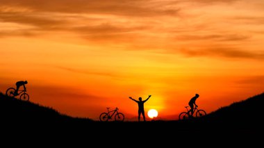 Doğada bisikletli bir kız ve bir oğlanın silueti.