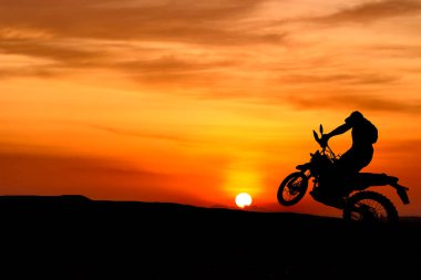 Güzel bir gün batımında motosikletli bir bisikletçinin silüeti..