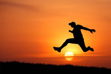 Sırt çantalı genç adam gün batımında yürüyor.