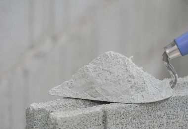 Şato üzerindeki harç yığını inşaat sahasında metin ve seçici odak için kopyalama alanı olan bir tuğla bloğa kondu                       