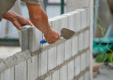 İnşaat alanına tuğla blokları döşeyen alüminyum tuğla malayla endüstriyel tuğla ustasının elleri.                                                           