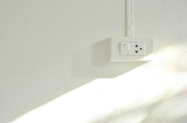 external light switch and sockets on white concrete wall background with sunshine reflection, copy space