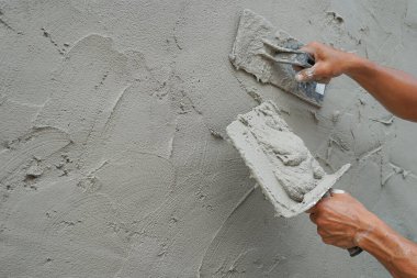 İnşaat alanındaki beton duvarları kopyalama alanı ile kaplayan bir işçi, seçici odak noktası olan alçı havan desenli detaylar                                    