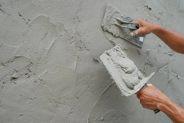 İnşaat alanındaki beton duvarları kopyalama alanı ile kaplayan bir işçi, seçici odak noktası olan alçı havan desenli detaylar                                    