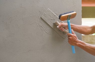 İnşaat alanında beton duvarları sıvayan işçilerin eli, seçici odaklanma                                                                                                 