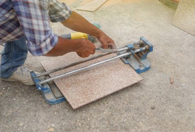 Fayans kesiciyle fayans kesen bir adam. Seçici bir odak noktası.                                                             