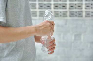 Plastik şişe sıkan bir adam. Plastik şişelerin geri dönüşüm için depolama alanı miktarını azaltmak, küresel ısınma alanının korunması için geri dönüşüm atıklarının sıralanması. Kopya alanı