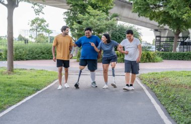 Şehir parkında spor kıyafetleriyle spor yapan bir grup insan. Protez bacaklı insanlar akşam güneşinde antrenman yaparken arkadaşlarıyla yürüyüp konuşmaktan zevk alıyorlar. 