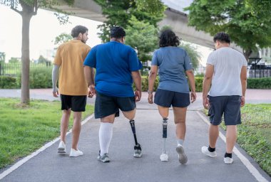 Şehir parkında spor giyim sporu yapan farklı insanlardan oluşan bir grup. Protez bacaklı kişi akşam güneşinde antrenman yaparken arkadaşlarıyla yürüyüp konuşmaktan zevk alıyor. 