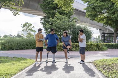 Şehir parkında spor kıyafetleriyle spor yapan bir grup insan. Protez bacaklı insanlar akşam güneşinde antrenman yaparken arkadaşlarıyla yürüyüp konuşmaktan zevk alıyorlar. 