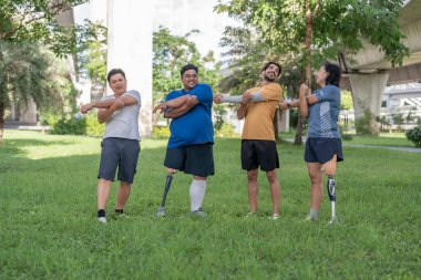Şehir parkında spor kıyafetleriyle spor yapan bir grup insan. Protez bacaklı insanlar akşam güneşinde antrenman yaparken arkadaşlarıyla yürüyüp konuşmaktan zevk alıyorlar. 