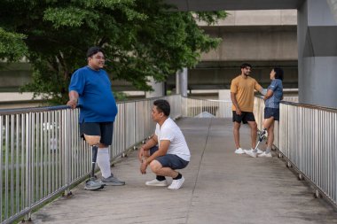 Şehirdeki çeşitli spor kıyafetleriyle gezen bir grup insan. Protez bacaklı insanlar. Akşamları antrenman sırasında arkadaşlarıyla yürüyüp konuşmaktan zevk alıyorlar.