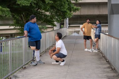 Şehirdeki çeşitli spor kıyafetleriyle gezen bir grup insan. Protez bacaklı insanlar. Akşamları antrenman sırasında arkadaşlarıyla yürüyüp konuşmaktan zevk alıyorlar.