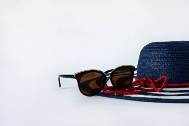 Büyük kenarlı ve beyaz arka planda güneş gözlüklü bir yaz şapkası. Yaz tatili için ürünler. Seyahat konsepti. Metin için boşluk