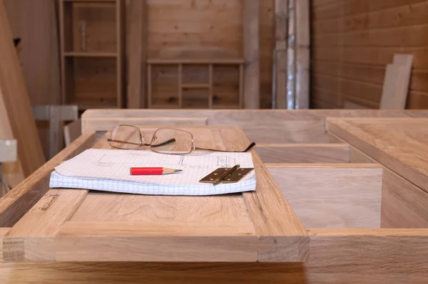 Production of furniture to order. Glasses, drawing, loop and pencil on the cabinet handmade from natural wood in light colors. Selective Focus