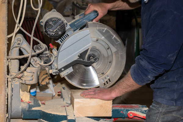 Производство деревянной мебели на заказ. Главный плотник выполняет резку заготовок на роторной пиле. Селективный фокус