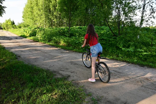 可爱的长发少女正在阳光灿烂的日子里学习骑自行车穿过夏村的街道 积极娱乐和体育的概念 — 图库照片