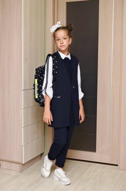 Saçında beyaz kurdele ve sırt çantalı güzel okul üniforması olan güzel bir kız. Okulun ilk günü. Okula dönelim. Bilgi Günü 'nde. Tam boy portre