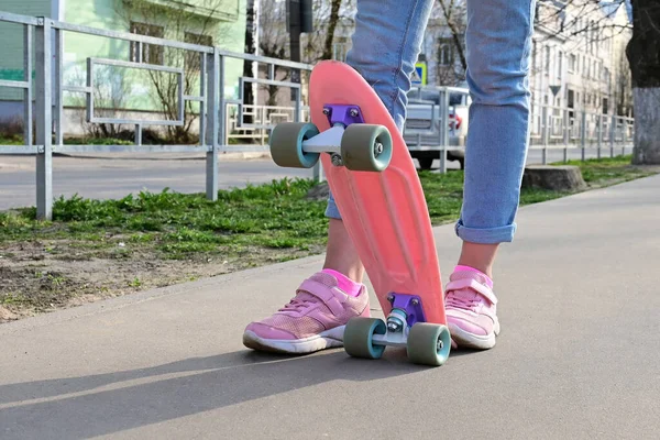 青いジーンズとピンクのスニーカーで女の子のスケートボーダーのクローズアップ足 ピンクのペニースケートロングボードに乗って 国際スケートボードの日 選択的焦点 — ストック写真