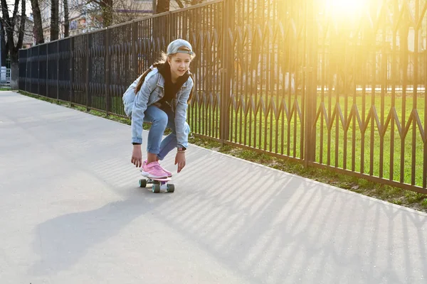 ジーンズとピンクのスニーカーを着た可愛い女の子が街中でペニースケートのロングボードに乗っています 国際スケートボードの日 スポーツ 開発コンセプト — ストック写真