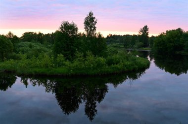 Gökyüzünde pembe bulutlar ile nehrin üzerinde gün doğumu, sakin suya yansıyor. Sabahın erken saatlerinde resim gibi. Yaratıcı bir imaj. Bu dünyadaki güzellik. Doğa kavramı