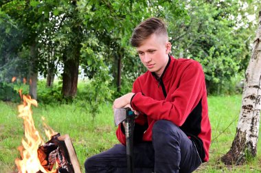 Ormandaki kamp ateşinde elinde baltası olan genç bir adam. Dinlenme zamanı. Biraz ara ver. Doğaya giden yol