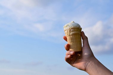Gözleme külahındaki dondurma, mavi yaz gökyüzünün arka planında. Küresel ısınma sorunu. Sıcak iklim. Boşluğu kopyala