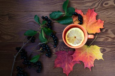 Sonbahar havası. Limonlu çay, dağ külleri ve ahşap bir masada renkli akçaağaç yaprakları. Üst manzaralı düz bir düzen. Merhaba, Eylül, Ekim, Kasım, mevsimlik konsept