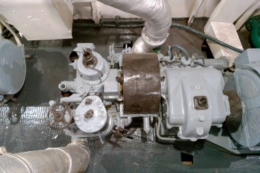 Bu sahne, çeşitli mekanik bileşenleri ve bağlı boruları vurgulayan, bir gemide karmaşık bir motor sistemi tasvir eder.