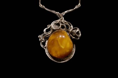 Güzel gümüş bir kolyede çarpıcı bir kehribar kolye bulunur. Kolye bir damlacık şeklinde, detaylı gümüş işçiliği ve gül tasarımlarıyla çevrili, ince işçiliği vurguluyor..