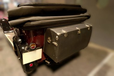 Klasik kırmızı bir araçta parlak bir tasarım, siyah yumuşak bir üst ve belirgin bir arka gövde bulunur. Sahne kapalı bir park alanında geçiyor, benzersiz tarzını vurguluyor..