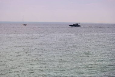 Bulutlu bir öğleden sonra iki tekne sakin sularda yüzer. Huzurlu sahne, rahatlatıcı kıyı yaşamının özünü yakalar..