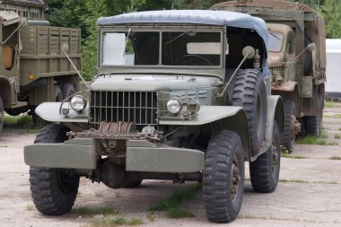 Kaliteli bir askeri kamyon, engebeli tasarımı ve sağlam özellikleriyle açık bir alanda duruyor. Yakınlarda ek askeri araçlar görülebilir..