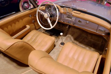 Üstü açık klasik iç döşeme, bronz deri koltuklar, klasik bir direksiyon ve iyi korunmuş bir otomotiv vitrininde retro vites..