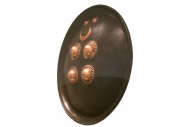 Detaylı bir Afrika kabile kalkanı, benzersiz metal dekorasyonlarla sergilenmektedir. Müze düzenlemelerinde geleneksel zanaat ve kültür mirasını temsil ediyor..