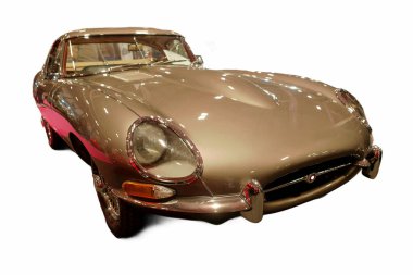 Klasik bir araba bir otomobil fuarında sergilenir. Aracın parlak bir vücudu, temiz çizgileri var ve olayın ışığını yansıtıyor. Salondaki diğer gösteriler arasında göze çarpıyor..