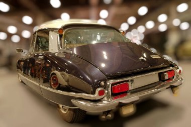 Klasik bir araba bir müzenin içine park edilmiştir. Ziyaretçiler ayrıntılı tasarım ve parlak dış görünüme bakmak için toplanıyorlar. Atmosfer canlı ve ilgiyle dolu..