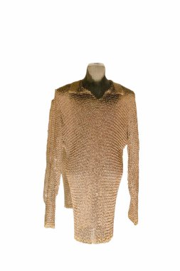 Zincirli bir gömlek bir mankenin üzerinde sunulur, karmaşık bağlantıları ve tasarımı vurgulanır. Bu parça ortaçağ işçiliğini ve zırhını temsil ediyor..