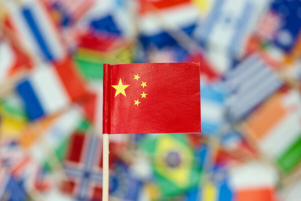 A small Chinese flag is in focus while many other flags from different countries can be seen in the background. This scene takes place at a cultural event celebrating world nations.