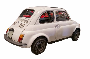 Bir araba fuarı sırasında küçük beyaz bir araba sergi alanında park edilir. Arabanın yuvarlak bir şekli ve basit bir tasarımı var. Parlak ışıklar aracı ve çevreyi vurguluyor.