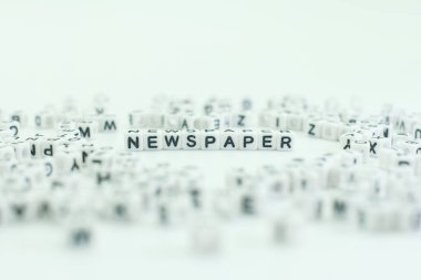 Beyaz bloklar, çeşitli harf bloklarıyla çevrili gazete sözcüğünü oluşturur. Bu sahne, arka planda bulunan harf bloklarının bir koleksiyonunu gösteriyor. Haber ve medya temasını vurgular.