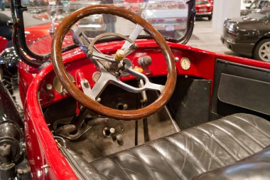 Eski model bir arabanın içinde ahşap bir direksiyon ve deri koltuklar bulunur. Gösterge panelinde göstergeler var ve ayarı da araba sergi salonu..